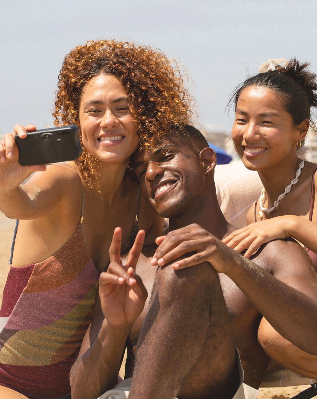 Group of friends smiling and taking a beach selfie, representing DONEDEO natural deodorant’s confidence-boosting, long-lasting freshness for all